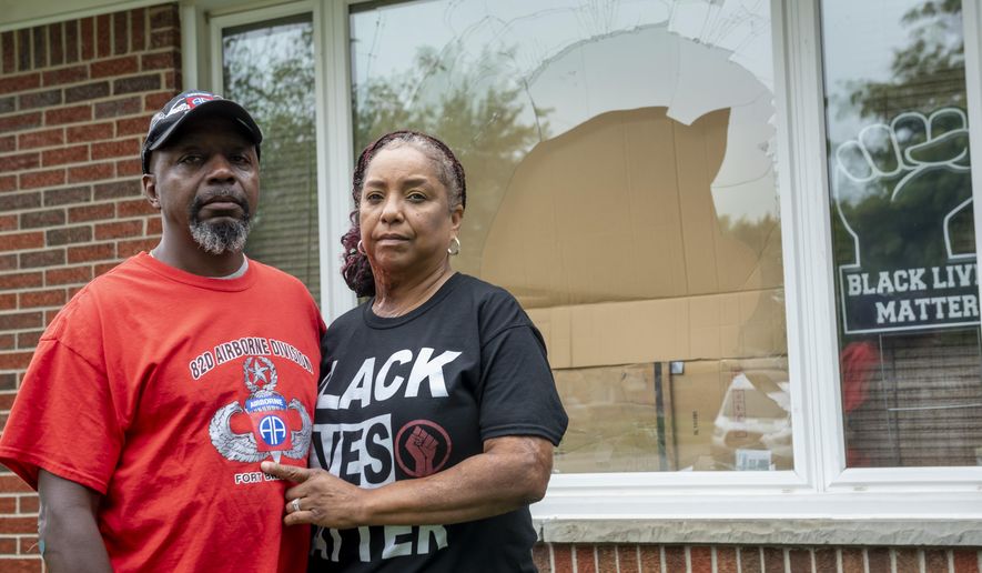 FILE - Eddie Hall Jr. and his wife Candace stand in front of the broken front window of their Warren, Mich., home, on Thursday, Sept. 10, 2020. Some experts say political and social unrest as well as the coronavirus pandemic has taken a disproportionate physical and financial tolls on Black people, resulting in increased anxiety levels among African Americans. (David Guralnick/Detroit News via AP, File)
