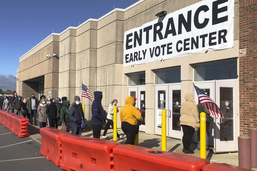 FILE - In this Friday, Oct. 30, 2020 file photo, people bundled against the cold stand in a slowly moving line to cast early votes at the Franklin County Board of Elections in Columbus, Ohio. Early voting ends in Ohio on Monday, Nov. 2. A surge in coronavirus cases across the country, including in key presidential battleground states, is creating mounting health and logistical concerns for voters, poll workers and political parties ahead of Election Day. (AP Photo/Andrew Welsh-Huggins)
