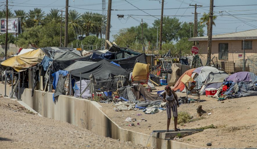 Homeless people begin their day as members of Food Not Bombs and the Sidewalk Project work to construct more huts for their housing at an encampment adjacent to the Interstate 15 north of West Owens Ave., Saturday, Aug. 15, 2020, in Las Vegas. City and state officials are raising concerns that perhaps thousands of homeless individuals in the Las Vegas area might have gone uncounted during the 2020 U.S. Census. (L.E. Baskow/Las Vegas Review-Journal via AP)