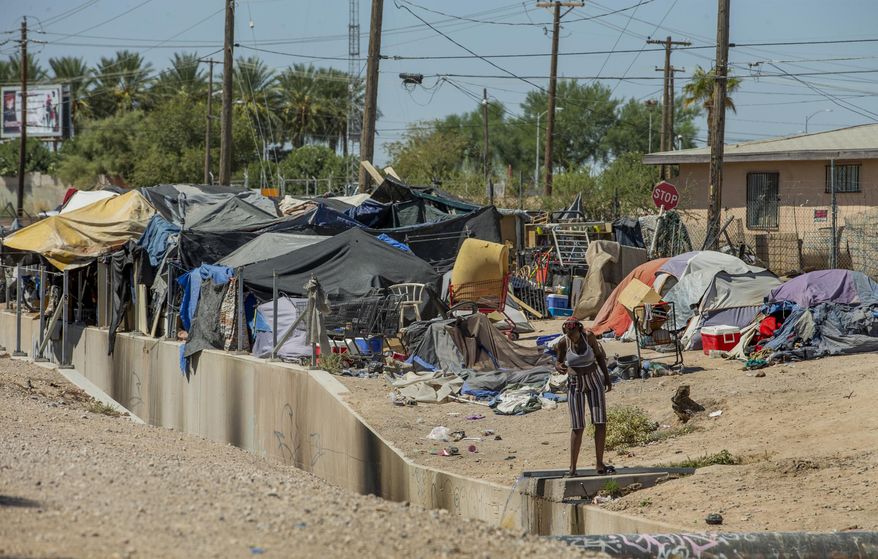 Homeless people begin their day as members of Food Not Bombs and the Sidewalk Project work to construct more huts for their housing at an encampment adjacent to the Interstate 15 north of West Owens Ave., Saturday, Aug. 15, 2020, in Las Vegas. City and state officials are raising concerns that perhaps thousands of homeless individuals in the Las Vegas area might have gone uncounted during the 2020 U.S. Census. (L.E. Baskow/Las Vegas Review-Journal via AP)