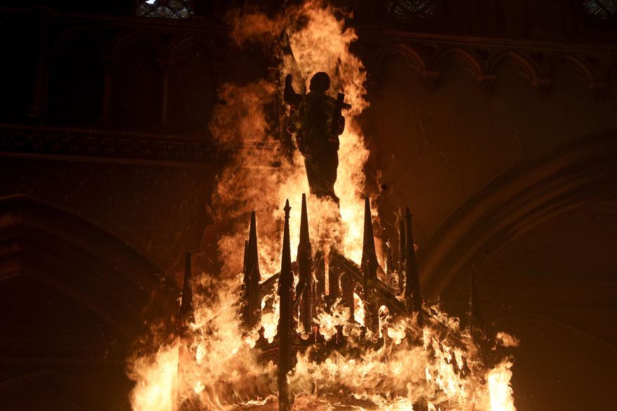 The statue of a saint is engulfed in flames after protesters torched the San Francisco de Borja church, a favorite of Chile's national police force, on the one-year anniversary of the start of anti-government mass protests over inequality in Santiago, Chile, Sunday, Oct. 18, 2020. (AP Photo/Esteban Felix)