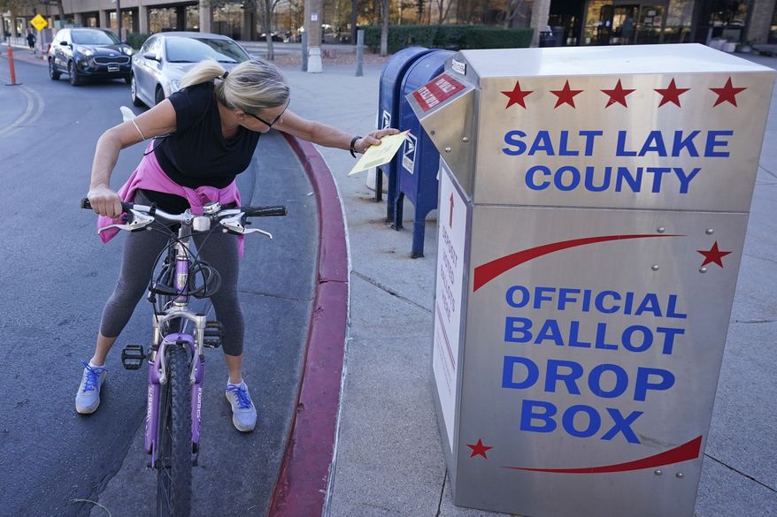 Debbie Sorensen inserts her ballot into a drops box Monday, Nov. 2, 2020, in Salt Lake City. (AP Photo/Rick Bowmer)
