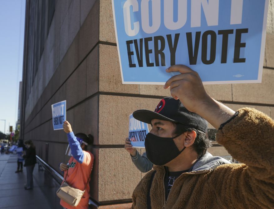 Sheridan Aguirre holds up a sign alongside fellow demonstrators who gathered outside the Bob Casey Federal Courthouse to voice their support of the drive through voting, which was available for early voters in Harris County, on Monday, Nov. 2, 2020, in Houston, Monday, Nov. 2, 2020. The lawsuit was brought by conservative Texas activists, who have railed against expanded voting access in Harris County, in an effort to invalidate nearly 127,000 votes in Houston because the ballots were cast at drive-thru polling centers established during the pandemic. (Godofredo A. Vásquez/Houston Chronicle via AP)