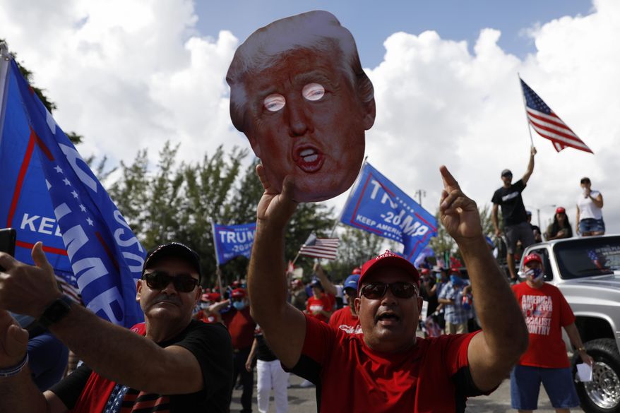 A man holds up a cardboard cutout of President Donald Trump as supporters rally ahead of the start of a car caravan by hundreds of vehicles, at Tropical Park in Miami, Sunday, Nov. 1, 2020.(AP Photo/Rebecca Blackwell)