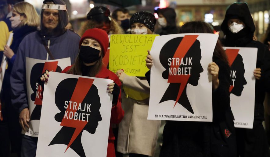 Protesters hold signs reading in Polish "women's strike" as they block a crossing in downtown Warsaw, Monday, Nov. 9, 2020, on the 12th straight day of anti-government protests that were triggered by the tightening of Poland's strict abortion law and are continuing despite a anti-COVID-19 ban on public gatherings. (AP Photo/Czarek Sokolowski)