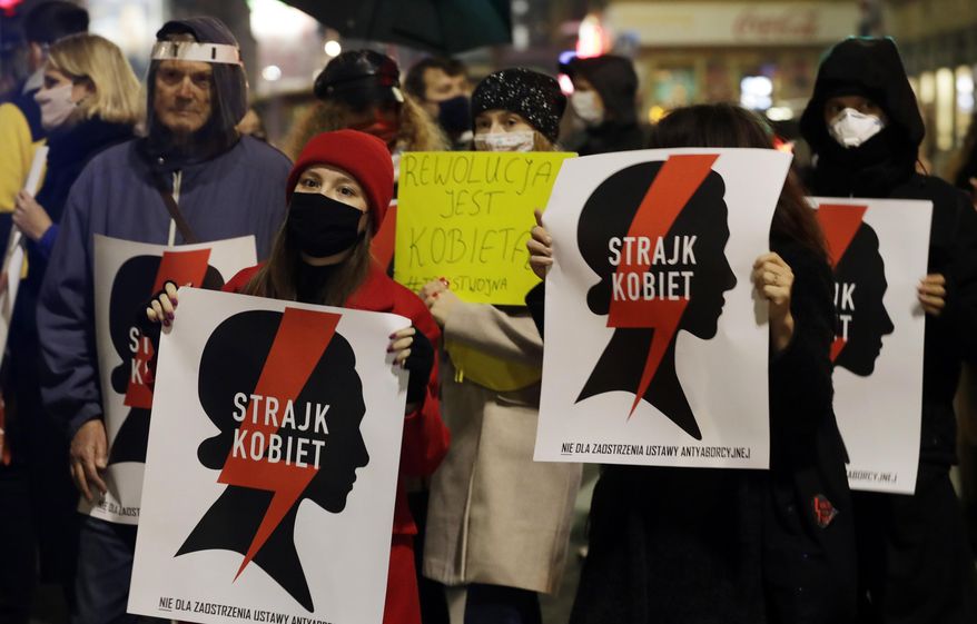 Protesters hold signs reading in Polish &amp;quot;women&#39;s strike&amp;quot; as they block a crossing in downtown Warsaw, Monday, Nov. 9, 2020, on the 12th straight day of anti-government protests that were triggered by the tightening of Poland&#39;s strict abortion law and are continuing despite a anti-COVID-19 ban on public gatherings. (AP Photo/Czarek Sokolowski)