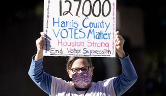 Demonstrator Gina Dusterhoft holds up a sign as she walks to join others standing across the street from the federal courthouse in Houston, Monday, Nov. 2, 2020, before a hearing in federal court involving drive-thru ballots cast in Harris County. The lawsuit was brought by conservative Texas activists, who have railed against expanded voting access in Harris County, in an effort to invalidate nearly 127,000 votes in Houston because the ballots were cast at drive-thru polling centers established during the pandemic. (AP Photo/David J. Phillip)