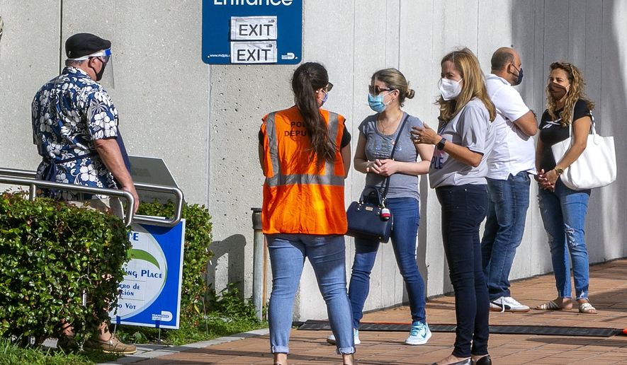 Congresswoman Debbie Mucarsel-Powell chats with poll employees as a group of people line up to vote at the Westchester regional Library early morning on Election Day on Tuesday, Nov. 3, 2020. (Pedro Portal/Miami Herald via AP)