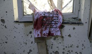A blood-stained Taliban flag is seen on the window inside the Kabul University after a deadly attack in Kabul, Afghanistan, Tuesday, Nov. 3, 2020. The brazen attack by gunmen who stormed the university has left many dead and wounded in the Afghan capital. The assault sparked an hours-long gun battle. (AP Photo/Rahmat Gul)