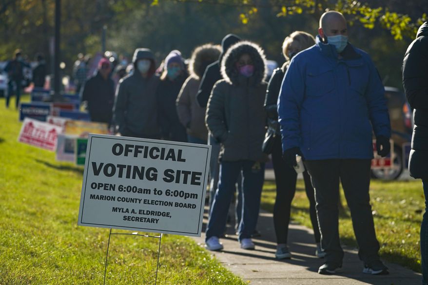 Voters wait in a line to cast their ballot at a polling place in Indianapolis, Tuesday, Nov. 3, 2020. (AP Photo/Michael Conroy)