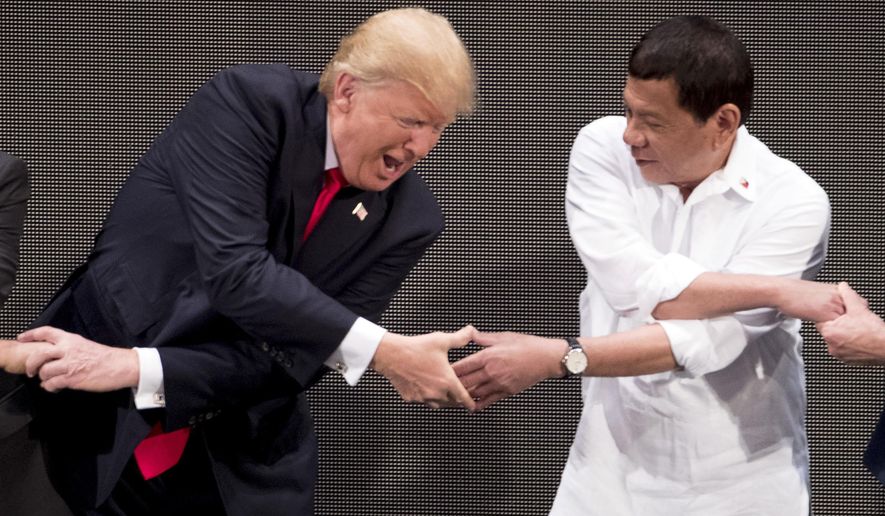 In this Nov. 13, 2017, file photo, U.S. President Donald Trump, left, reacts as he does the &#39;ASEAN-way handshake&#39; with Vietnamese Prime Minister Nguyen Xuan Phuc, not pictured, and Philippine President Rodrigo Duterte on stage during the opening ceremony at the ASEAN Summit at the Cultural Center of the Philippines, in Manila. The 2020 ASEAN Summit is being conducted virtually but Mr. Trump is not in attendance this year. (AP Photo/Andrew Harnik, File)
