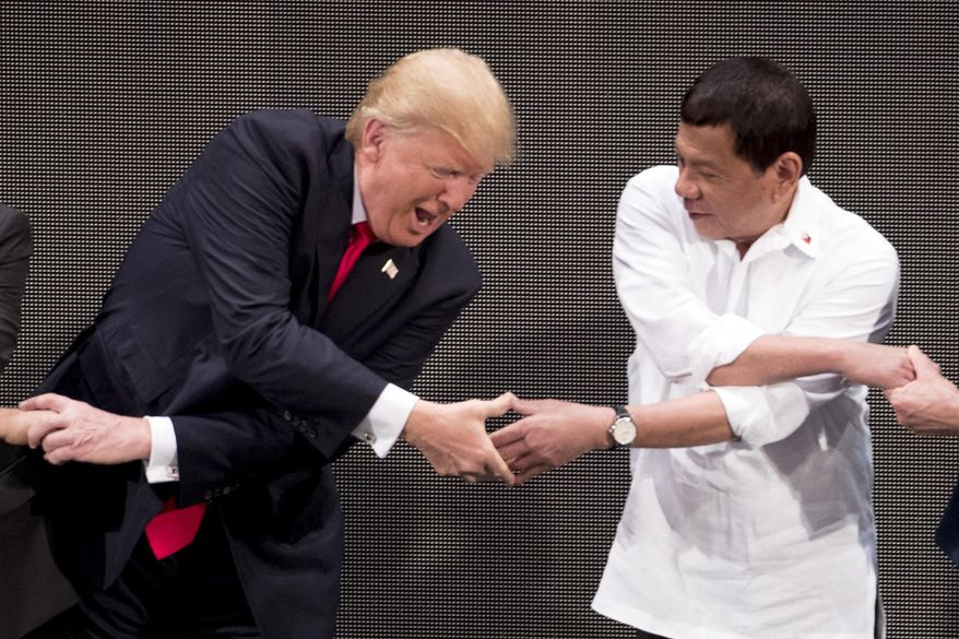 In this Nov. 13, 2017, file photo, U.S. President Donald Trump, left, reacts as he does the &#39;ASEAN-way handshake&#39; with Vietnamese Prime Minister Nguyen Xuan Phuc, not pictured, and Philippine President Rodrigo Duterte on stage during the opening ceremony at the ASEAN Summit at the Cultural Center of the Philippines, in Manila. The 2020 ASEAN Summit is being conducted virtually but Mr. Trump is not in attendance this year. (AP Photo/Andrew Harnik, File)