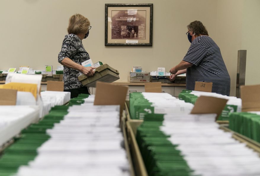 Election workers Mary Pluszczynsky, left, and Michelle Derringer bring out trays of ballots while setting up for election inspectors to count ballots on Election Day at City Hall in Warren, Mich., Tuesday, Nov. 3, 2020. (AP Photo/David Goldman) **FILE**