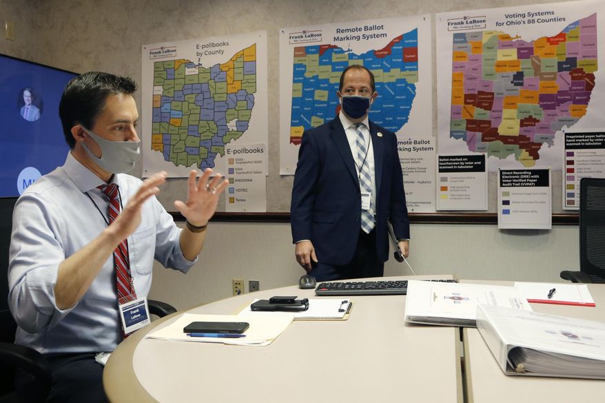 Ohio Secretary of State Frank LaRose, left, interacts with staff members as they follow the election from Ohio's election command center Tuesday, Nov. 3, 2020, in Columbus, Ohio. (AP Photo/Jay LaPrete)