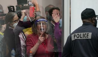 Election challengers yell as they look through the windows of the central counting board as police were helping to keep additional challengers from entering due to overcrowding, Wednesday, Nov. 4, 2020, in Detroit. (AP Photo/Carlos Osorio)