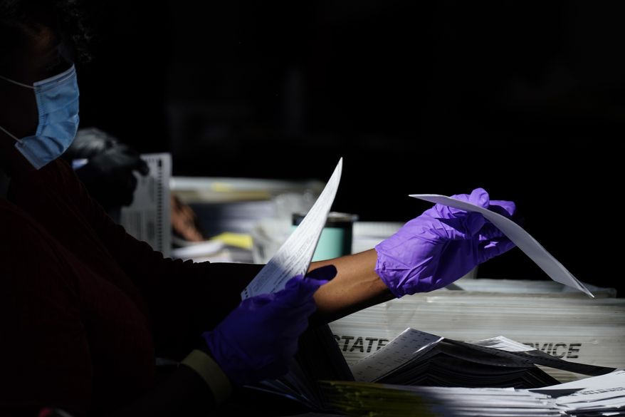 An election personnel counts ballots as votes are counted at State Farm Arena on Wednesday, Nov. 4, 2020, in Atlanta. (AP Photo/Brynn Anderson)