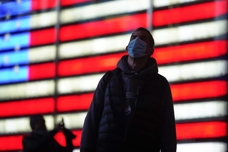A man stops to watch election returns on electronic billboards in Times Square, Tuesday, Nov. 3, 2020, in New York. (AP Photo/Seth Wenig)