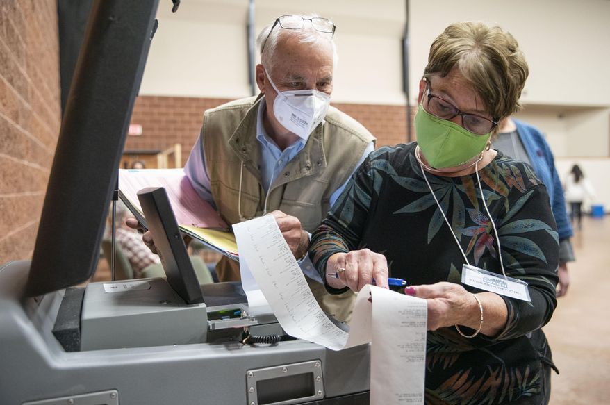 John Keenan, left, and Kathie Trotta, Duluth's 11th precinct co-head polling judges, read off the in-person ballot counts for the presidential and U.S. Senate races to an Associated Press representative after the polls closed, Tuesday, Nov. 3, 2020, in Duluth, Minn. (Alex Kormann/Star Tribune via AP)