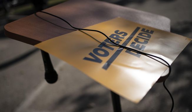 A sign that reads &amp;quot;Voters Decide&amp;quot; is placed next to a hanging microphone as people gather at the Civic Center Park while waiting for the results of election, Wednesday, Nov. 4, 2020, in Kenosha, Wis. (AP Photo/Wong Maye-E)