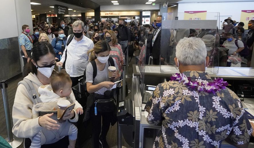 FILE - In this Oct. 15, 2020, file photo, United Airlines passengers walk past through the gate to board a flight to Hawaii at San Francisco International Airport in San Francisco. Health officials in the San Francisco Bay area are considering advising residents who travel outside the area during the upcoming holiday season to quarantine when they return to try to prevent a spike in virus cases. The proposal comes as California has seen coronavirus cases inch up recently, though the infection rate in the nation's most populous state remains much lower than the country as a whole. (AP Photo/Jeff Chiu, File)