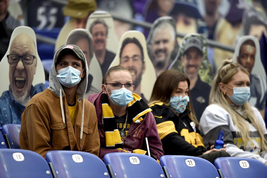 In this Nov. 1, 2020, file photo, specators wear a face masks to protect against COVID-19 during the first half of an NFL football game between the Baltimore Ravens and the Pittsburgh Steelers, in Baltimore. A new set of rules are coming in just about every sport, almost all with enhanced health and safety in mind. If they work, games could get out of bubbles and return to arenas and stadiums with some fans in attendance sometime soon. Perhaps more importantly, they could also provide some common-sense solutions to virus issues in the real world.(AP Photo/Gail Burton, File) **FILE**