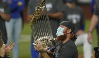  In this Tuesday, Oct. 27, 2020, file photo, Los Angeles Dodgers third baseman Justin Turner celebrates with the trophy after defeating the Tampa Bay Rays 3-1 to win the baseball World Series in Game 6 in Arlington, Texas. Baseball nearly made it through its version of playoff bubbles unscathed; two innings before the World Series ended, Justin Turner of the now-champion Los Angeles Dodgers Turner was pulled from the game after MLB was notified that he had tested positive for COVID-19. (AP Photo/Eric Gay, File)  **FILE**