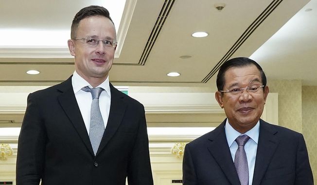 Hungarian Foreign Minister Peter Szijjarto, left, poses with Cambodian Prime Minister Hun Sen for a photo prior to a meeting at Peace Palace in Phnom Penh, Cambodia, Tuesday, Nov. 3, 2020. Szijjarto tested positive for the coronavirus after arriving in Thailand for an official visit, Thai and Hungarian officials said Wednesday, Nov. 4, 2020. (Pool Photo via AP)