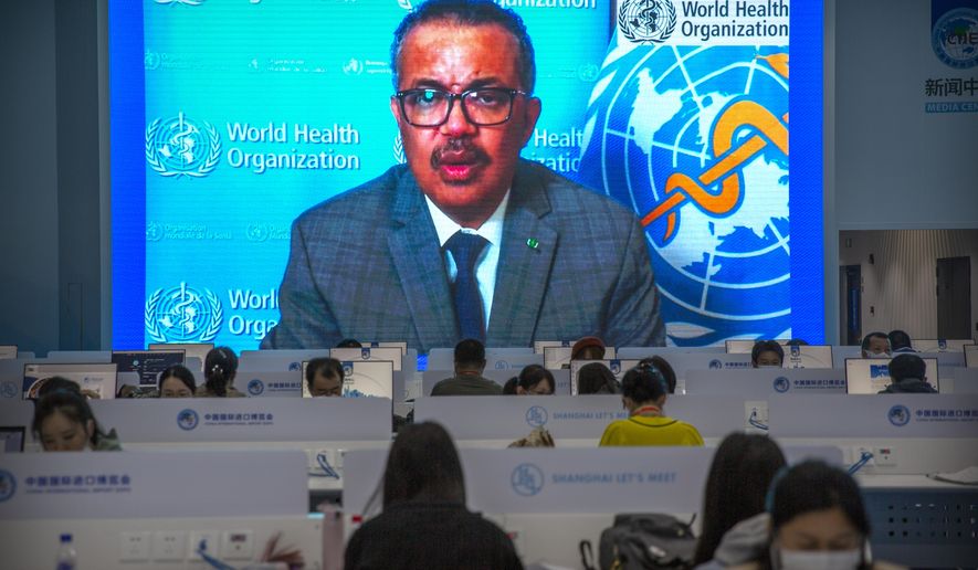 Journalists wearing face masks to protect against the coronavirus work as video screens show World Health Organization chief Tedros Adhanom Ghebreyesus delivering a prerecorded address to the opening ceremony of the China International Import Expo in Shanghai, Wednesday, Nov. 4, 2020. The expo, one of China&#39;s largest annual trade fairs, kicks off on Thursday as the ongoing COVID-19 pandemic has largely been controlled within China. Ghebreyesus announced this week that he would self-quarantine after being identified as a contact of a person who tested positive for COVID-19. (AP Photo/Mark Schiefelbein)