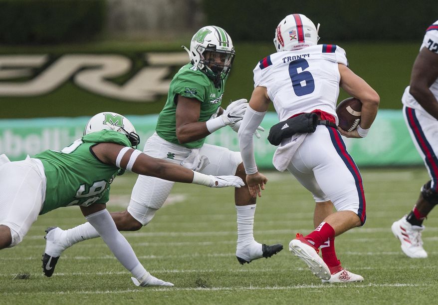 Marshall defensive tackle Jamare Edwards (99) and linebacker Tavante Beckett (4) attempt to bring down Florida Atlantic quarterback Nick Tronti (6) during an NCAA college football game on Saturday, Oct. 24, 2020, at Joan C. Edwards Stadium Huntington, W.Va. (Sholten Singer/The Herald-Dispatch via AP)