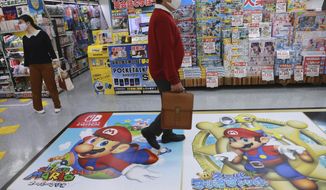 A shopper passes by an ad for Super Mario of Nintendo at an electronics store in Tokyo, Monday, Nov. 2, 2020. (Nintendo, the Japanese company behind Super Mario and Pokemon video games, reported Thursday that its fiscal first half profit more than tripled as passed time while stuck at home during the pandemic playing games. AP Photo/Koji Sasahara)