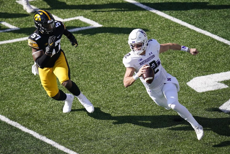 Northwestern quarterback Peyton Ramsey runs from Iowa defensive lineman Chauncey Golston (57) during the first half of an NCAA college football game, Saturday, Oct. 31, 2020, in Iowa City, Iowa. (AP Photo/Charlie Neibergall)