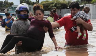 A pregnant woman is carried out of an area flooded by water brought by Hurricane Eta in Planeta, Honduras, Thursday, Nov. 5, 2020. The storm that hit Nicaragua as a Category 4 hurricane on Tuesday had become more of a vast tropical rainstorm, but it was advancing so slowly and dumping so much rain that much of Central America remained on high alert. (AP Photo/Delmer Martinez)