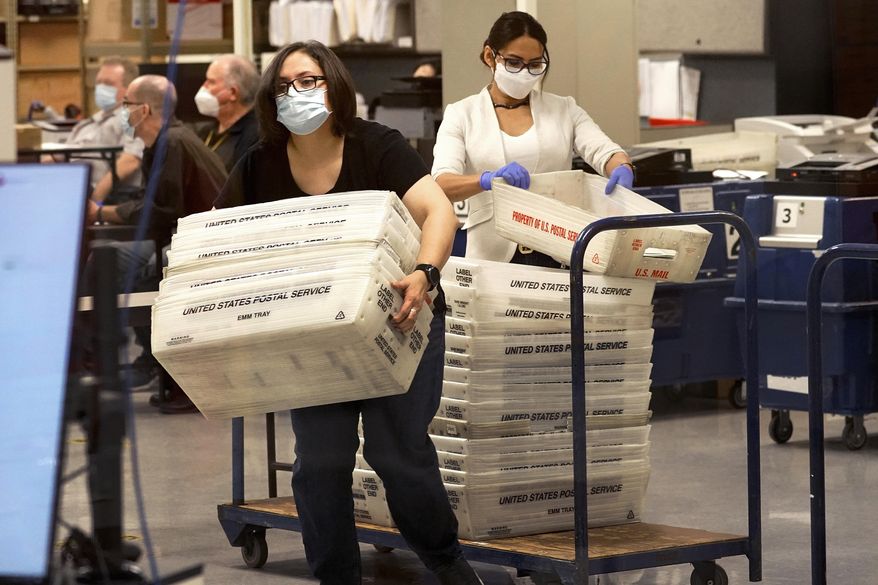 Arizona elections officials carry ballots in trays to be counted inside the Maricopa County Recorder's Office, Friday, Nov. 6, 2020, in Phoenix. (AP Photo/Matt York) ** FILE **