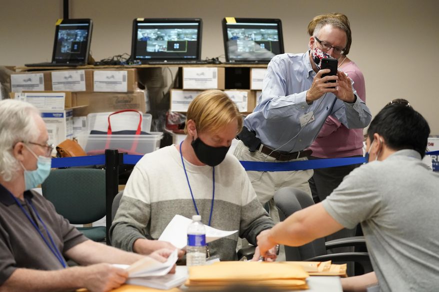Republican canvas observer Ed White, takes photos with his smart phone as Lehigh County workers count ballots as vote counting in the general election continues, Friday, Nov. 6, 2020, in Allentown, Pa. (AP Photo/Mary Altaffer)