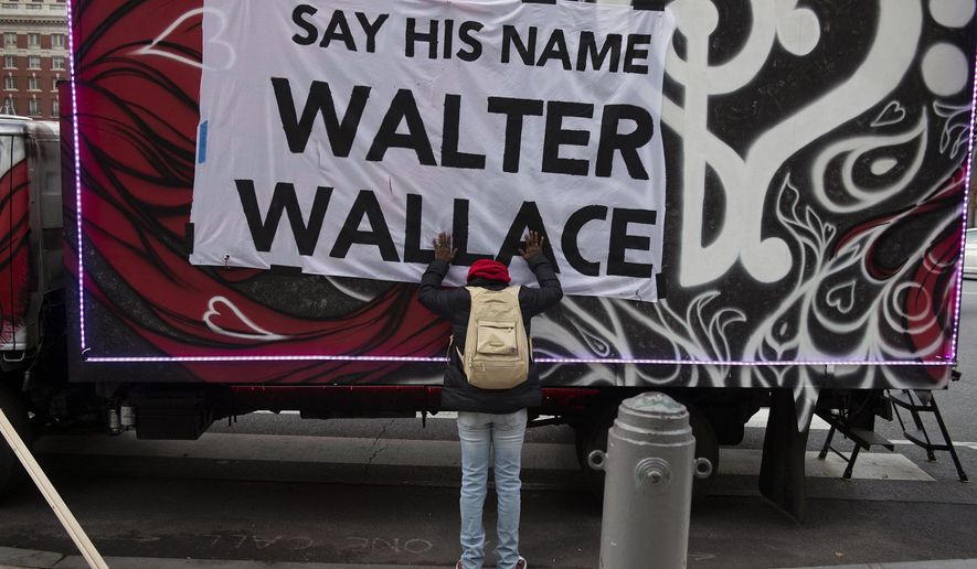 Sheila Rhames rests her hands on a banner honoring Walter Wallace Jr. in Philadelphia, Wednesday, Nov. 4, 2020. Wallace, a Black man, was shot and killed by police in West Philadelphia, last month. Rhames was his neighbor. (Joe Lamberti/Camden Courier-Post via AP)