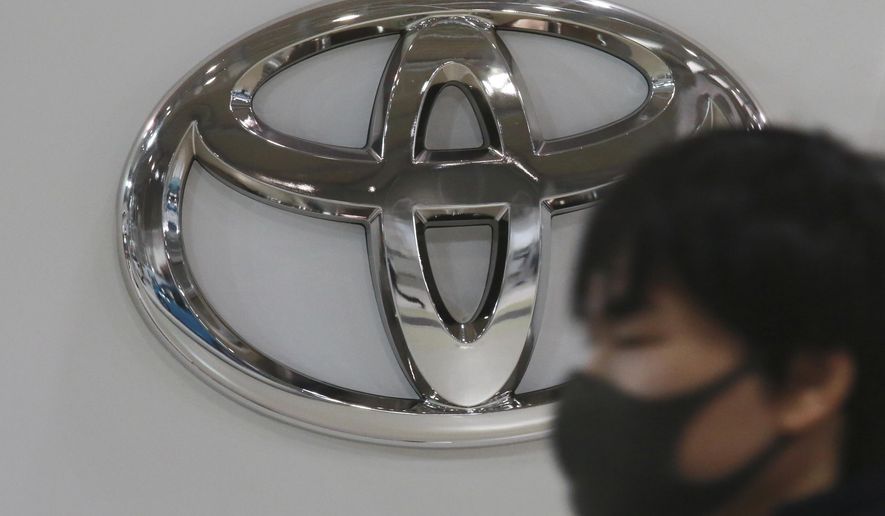 A visitor wearing a face mask to help curb the spread of the coronavirus walks by the logo of Toyota Motor Corp. at its showroom in Tokyo, Monday, Nov. 2, 2020. Toyota’s July-September profit fell 11% as the coronavirus pandemic slammed global demand, but Japan’s top automaker appeared to be holding up well, compared to weaker rivals that have sunk into the red. (AP Photo/Koji Sasahara)