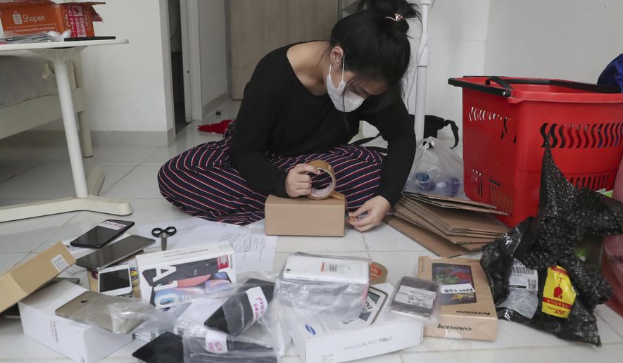 Indonesian journalist Ghina Ghaliya pack used mobile phones before shipping them to underprivileged children who lack internet access to study online, at her apartment in Tangerang, Indonesia, on Sept. 25, 2020. When a garbage collector came to Ghaliya's house and asked if she had an old mobile phone his children could use to access the internet, it sparked an idea for a broader campaign to help students stuck at home by the coronavirus. (AP Photo/Tatan Syuflana)