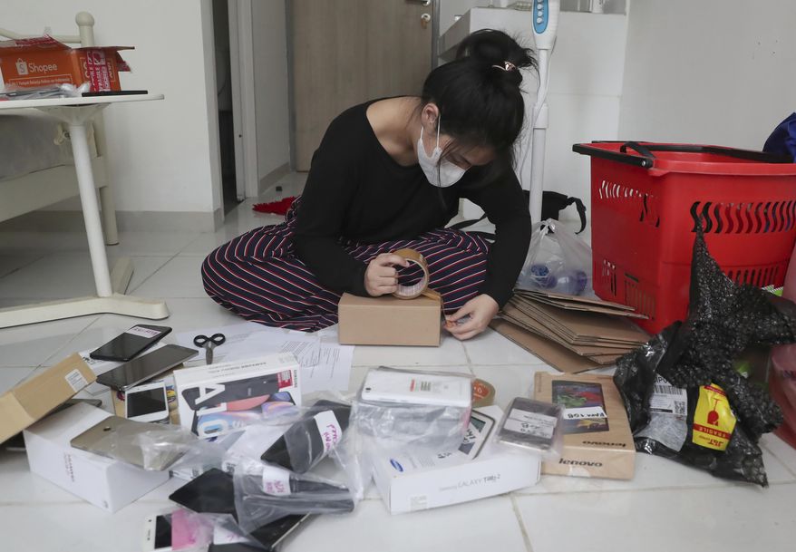 Indonesian journalist Ghina Ghaliya pack used mobile phones before shipping them to underprivileged children who lack internet access to study online, at her apartment in Tangerang, Indonesia, on Sept. 25, 2020. When a garbage collector came to Ghaliya's house and asked if she had an old mobile phone his children could use to access the internet, it sparked an idea for a broader campaign to help students stuck at home by the coronavirus. (AP Photo/Tatan Syuflana)