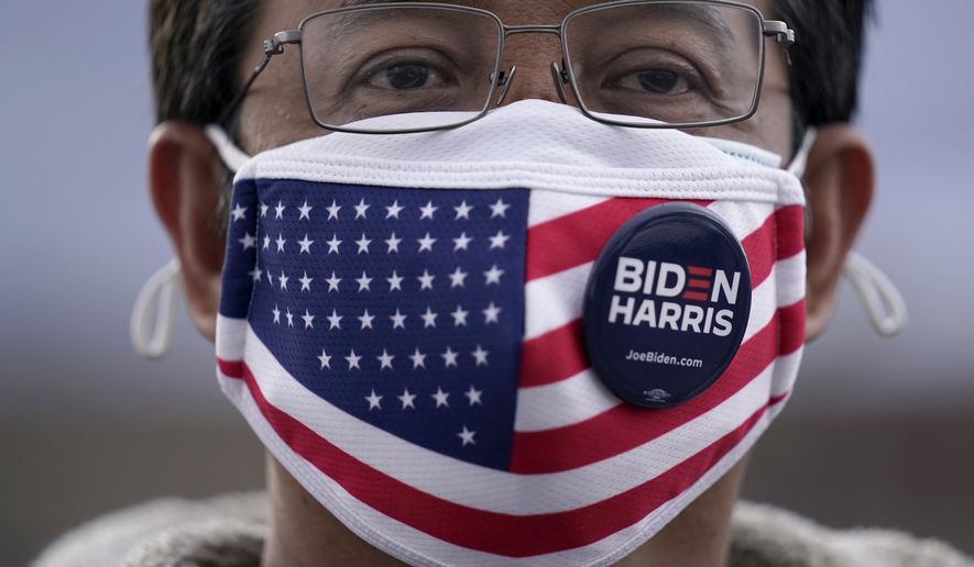 Felipe Danglapin wears a pin supporting President-elect Joe Biden and Vice President-elect Kamala Harris on his face mask in Las Vegas, Saturday, Nov. 7, 2020. Biden defeated President Donald Trump to become the 46th president of the United States on Saturday, positioning himself to lead a nation gripped by the historic pandemic and a confluence of economic and social turmoil. (AP Photo/Jae C. Hong)