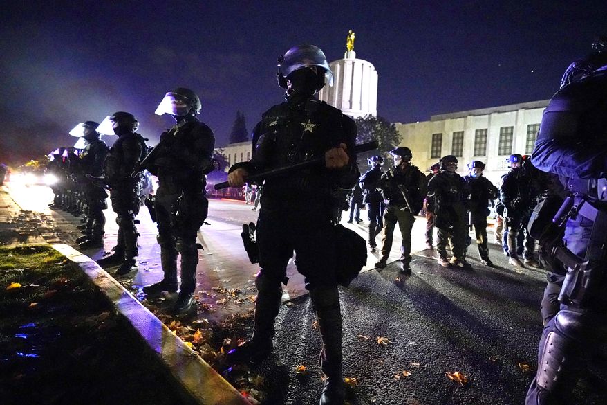 Police line-up at the Oregon State Capitol building where demonstrators gathered during the day Saturday, Nov 7, 2020, in Salem, Ore. Democrat Joe Biden defeated President Trump to become the 46th president of the United States on Saturday. (AP Photo/Marcio Jose Sanchez)
