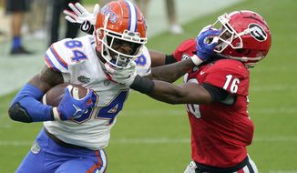 Florida tight end Kyle Pitts (84) tires to get past Georgia defensive back Lewis Cine (16) after a reception during the first half of an NCAA college football game, Saturday, Nov. 7, 2020, in Jacksonville, Fla. (AP Photo/John Raoux)