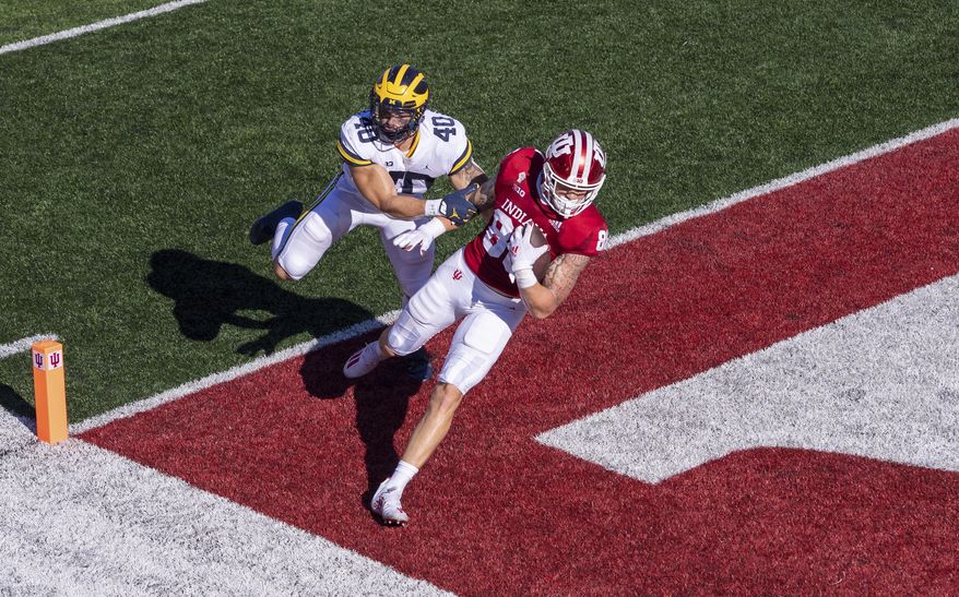 Indiana tight end Peyton Hendershot (86) crosses into the end zone to score ahead of Michigan linebacker Ben VanSumeren (40) during the first half of an NCAA college football game Saturday, Nov. 7, 2020, in Bloomington, Ind. (AP Photo/Doug McSchooler)