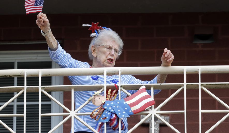 A resident of the Lambeth House, where a cluster of the coronavirus has formed, reacts from her balcony as opera singers Irini Hymel and Bryan Hymel sing to the quarantined residents in New Orleans, Friday, March 20, 2020. (AP Photo/Gerald Herbert)