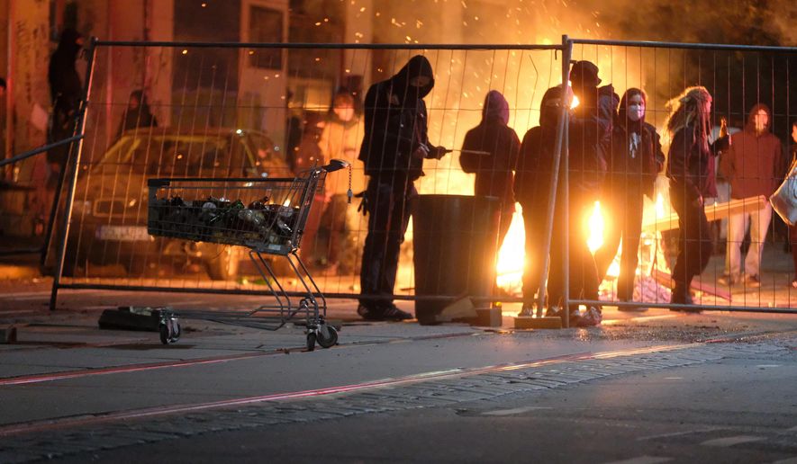 People stand at a burning barricade during riots in the Connewitz district, Saturday, Nov. 7, 2020, in Leipzig, Germany. Several thousand people took part in the rally against the corona measures adopted by the federal and state governments. (Sebastian Willnow/dpa via AP)