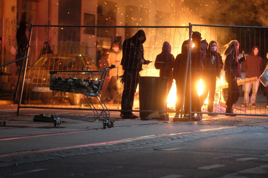 People stand at a burning barricade during riots in the Connewitz district, Saturday, Nov. 7, 2020, in Leipzig, Germany. Several thousand people took part in the rally against the corona measures adopted by the federal and state governments. (Sebastian Willnow/dpa via AP)