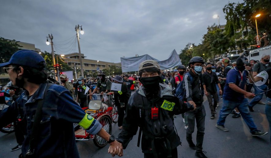 Front line pro-democracy protesters lead a march with linked-arms in Bangkok, Thailand, Sunday, Nov. 8, 2020. The protesters continue to gather Sunday, led by their three main demands of Prime Minister Prayuth Chan-ocha's resignation, changes to a constitution that was drafted under military rule and reforms to the constitutional monarchy. (AP Photo/Sakchai Lalit)