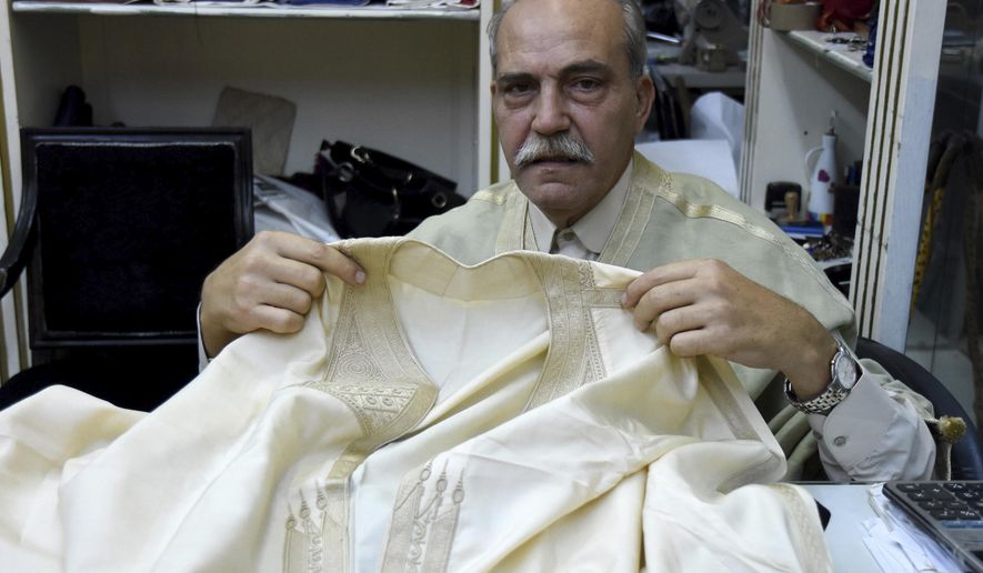 Lasaad El Beji Amine El Hrairia, a silk weaver In Tunis&#39; Medina and that Hassan Ben Ayech, the designer for the Bardo Collection, uses, holds a fabric in Tunis, Monday Oct.5 , 2020. El Béji is an example of a local Tunisian artisan whose craft and production of high-quality hand-made material is being incorporated by these new sustainable fashion brands. (AP Photo/Hassene Dridi)
