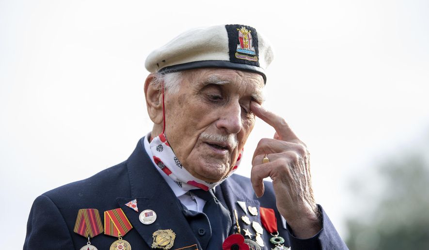 Seymour 'Bill' Taylor, 95, from Colchester, who served as an Able Seaman in the Royal Navy onboard HMS Emerald during the D-Day landings joins neighbours in the street to observe the two minutes silence to pay his respects on Remembrance Sunday, in Essex, England, Sunday, Nov. 8, 2020. (Joe Giddens/PA via AP)