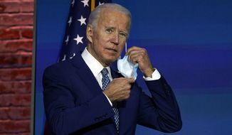 President-elect Joe Biden removes his face mask as he arrives to speak Monday, Nov. 9, 2020, at The Queen theater in Wilmington, Del. (AP Photo/Carolyn Kaster)