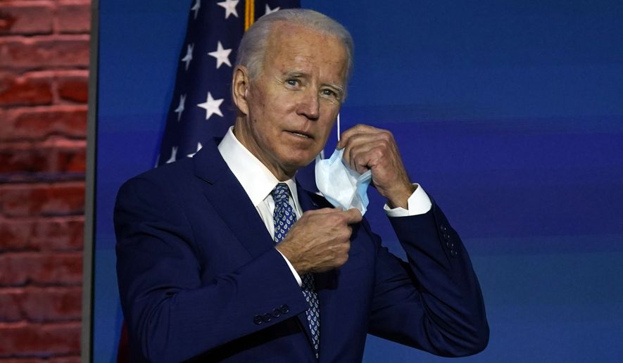 President-elect Joe Biden removes his face mask as he arrives to speak Monday, Nov. 9, 2020, at The Queen theater in Wilmington, Del. (AP Photo/Carolyn Kaster)